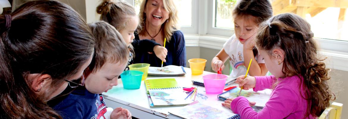 home child care provider and home child care manager at small table with children who are painting